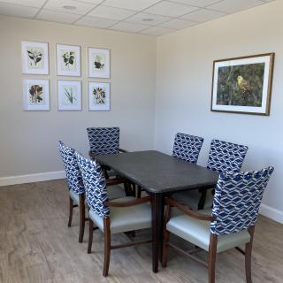A dining room with a table and patterned chairs, adorned with wall art.