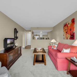 A cozy living room with a red sofa, wooden furniture, and colorful artwork.