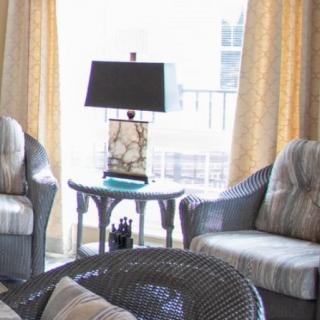 A cozy living room setup with cushioned chairs and a lamp on a side table near a window with curtains.