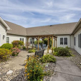 A serene courtyard garden with a pergola and seating area surrounded by lush landscaping.