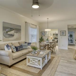 A modern and cozy living room with a neutral color scheme, featuring a sofa and coffee table, and an adjacent dining area.