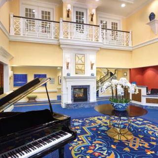 A luxurious hotel lobby featuring a grand piano, elegant decor, and a cozy fireplace.