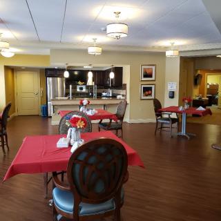 A cozy dining area with red tablecloths and a well-lit kitchen in the background.
