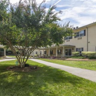 A sunny day view of a residential building with a landscaped lawn and pathway.