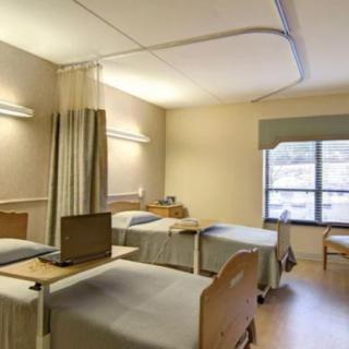 A hospital ward with multiple beds separated by curtains.