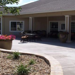 A cozy patio area with outdoor seating surrounded by landscaped gardens and potted plants.