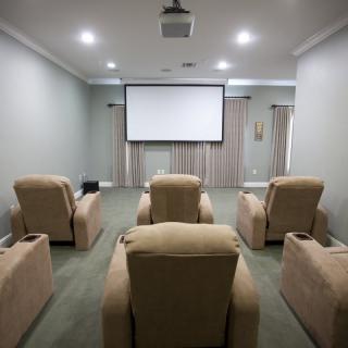 A cozy home theater setup with a projector and comfortable recliner chairs.