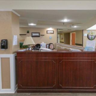 A reception area with a wooden desk and a person seated behind it in a lobby setting.