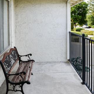 A quiet balcony with a wooden bench and metal railings.