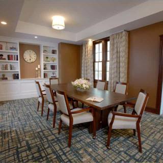 A well-appointed conference room featuring a large table surrounded by chairs, with bookshelves and elegant decor.