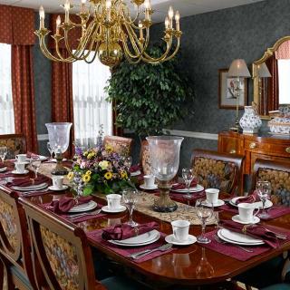 An elegantly set dining room table with a chandelier overhead and classic decor.