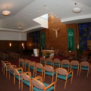 An interior view of a church featuring an altar, seating arrangements, and a crucifix on the wall.