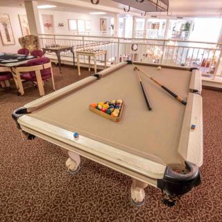 A pool table set up in a spacious game room with cues and racked balls ready for play.