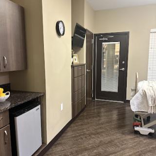 A modern interior featuring a kitchenette, clock, and door leading to the outside.