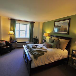 A cozy bedroom with a neatly made bed, ambient lighting, and elegant decor.