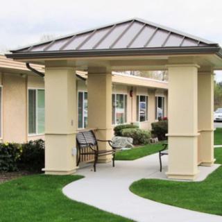 A well-maintained building entrance with a pathway and bench.