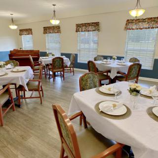 An elegantly arranged dining room with tables set for a meal, featuring white tablecloths and inviting decor.