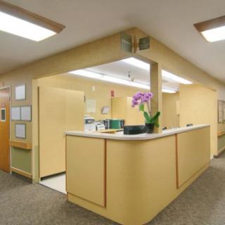 A reception area with a beige color scheme and indoor lighting, featuring a counter and office decor.