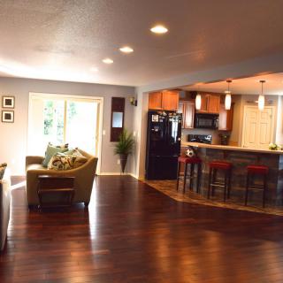 A modern open floor plan featuring a spacious living room and kitchen with hardwood flooring.