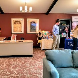 A reception area with a desk and two people interacting near display tables.