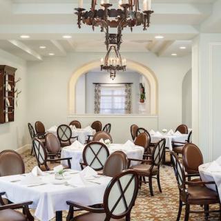 An elegant dining room with neatly set tables and a classic chandelier.