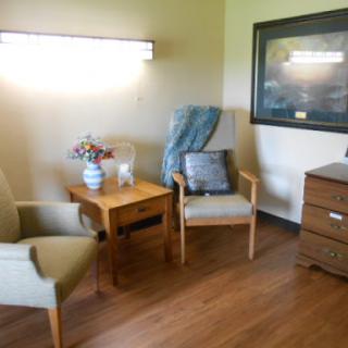 A cozy corner featuring two chairs, a wooden table, and a dresser, creating a warm living space.