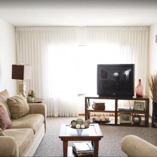 A cozy living room with a sofa, coffee table, and television, featuring neutral tones and elegant decor.