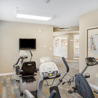 A fitness room equipped with stationary bikes and a television.