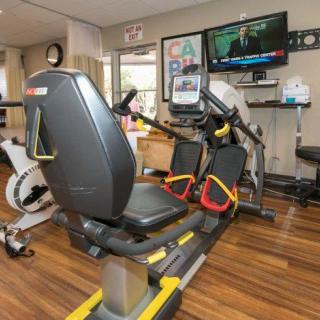 A gym with a recumbent exercise bike and a television mounted on the wall.
