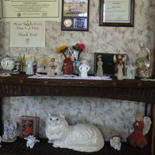 A decorative shelf displaying various figurines, certificates, and a clock.