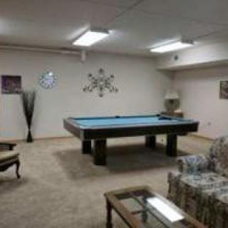 A basement game room featuring a pool table, sofa, and coffee table.