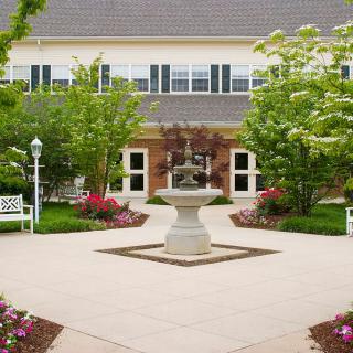 A peaceful courtyard with a central fountain surrounded by a well-maintained garden and building.