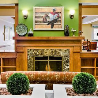 A cozy living room features a wooden fireplace with a green accent wall and elegant decor.