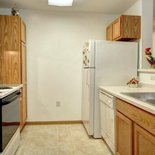A compact kitchen with wooden cabinets, white appliances, and a clean countertop.