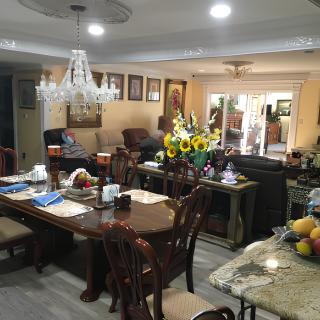 A cozy and well-decorated dining and living room with a chandelier, table settings, and sunflowers adding a warm touch.