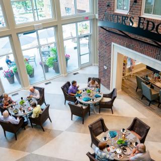 Aerial view of a bright and spacious dining area with people seated at round tables, socializing and enjoying meals.