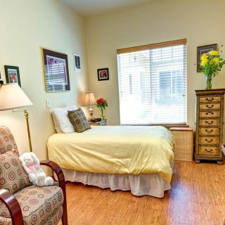 A cozy bedroom with a single bed, floral decor, and wooden furniture.