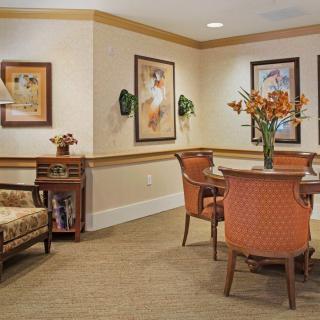 A cozy living room with comfortable seating, decorative artwork on the walls, and a vase of flowers on the table.