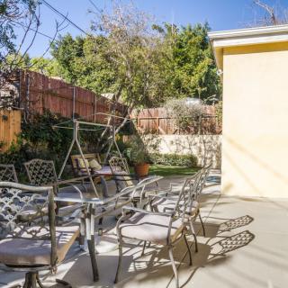 A sunny patio with metal chairs and a view of a garden.