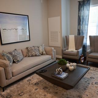 A modern living room with a sofa, two chairs, a coffee table, and wall art.
