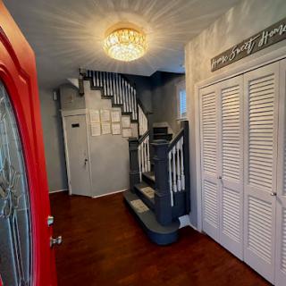 A cozy and inviting entrance hall featuring a stylish staircase and a bright red door.