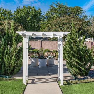 A beautiful garden archway leading to a landscaped area with lush greenery.