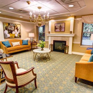 A cozy living room with elegant furniture, vibrant decor, and a warm fireplace.
