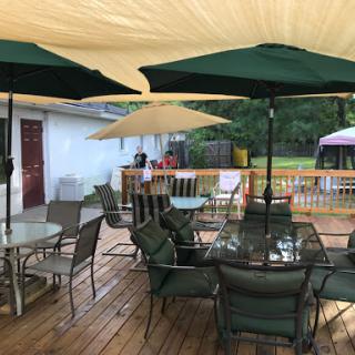 A cozy outdoor patio setup with green umbrellas and wooden decking, perfect for relaxation.