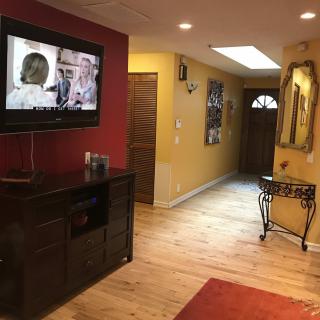 A cozy living space with hardwood flooring, a wall-mounted television, and decorative elements.