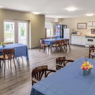 A bright and spacious community dining area with tables covered in blue tablecloths.