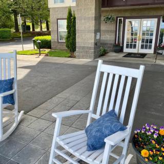 A cozy porch entrance with white rocking chairs and colorful flowers.