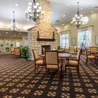 A cozy dining area with a central stone fireplace, chandeliers, and elegant furniture.