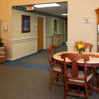 A welcoming dining area with a table and chairs, adorned with flowers, leading to a hallway.
