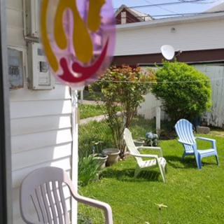 A sunny backyard with colorful chairs on a green lawn.